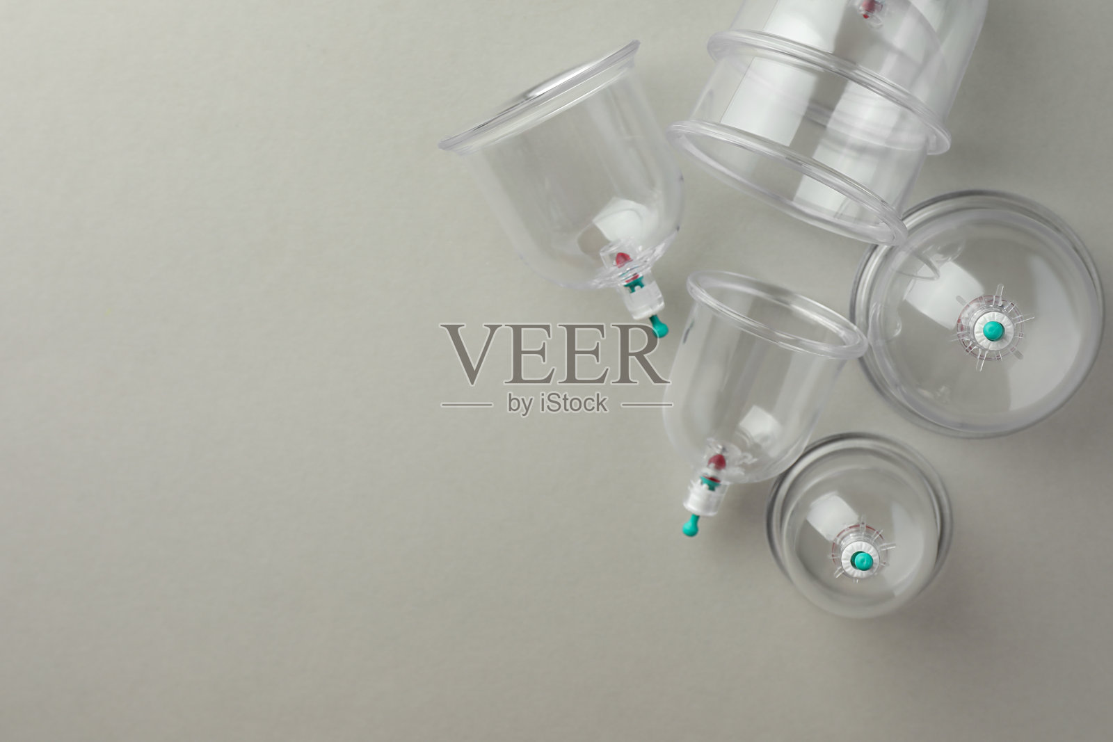 浅灰色背景上的塑料杯,平铺着文字空间。拔火罐照片摄影图片