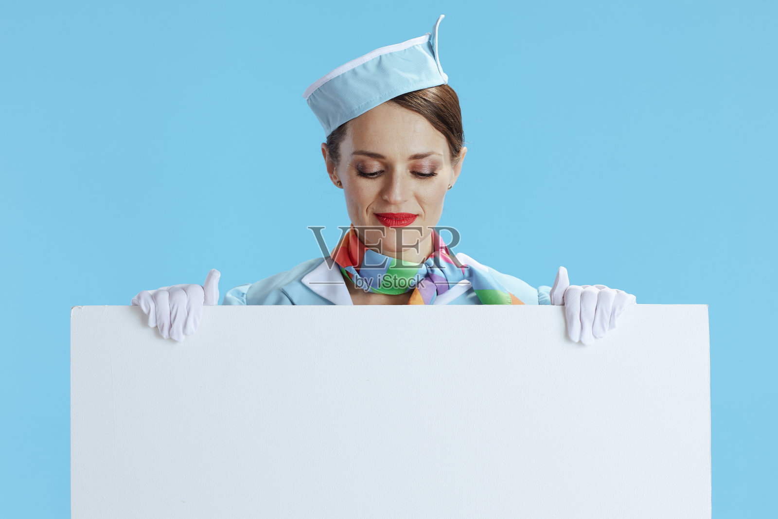 优雅的空乘女士穿蓝色衣服,露出白板照片摄影图片