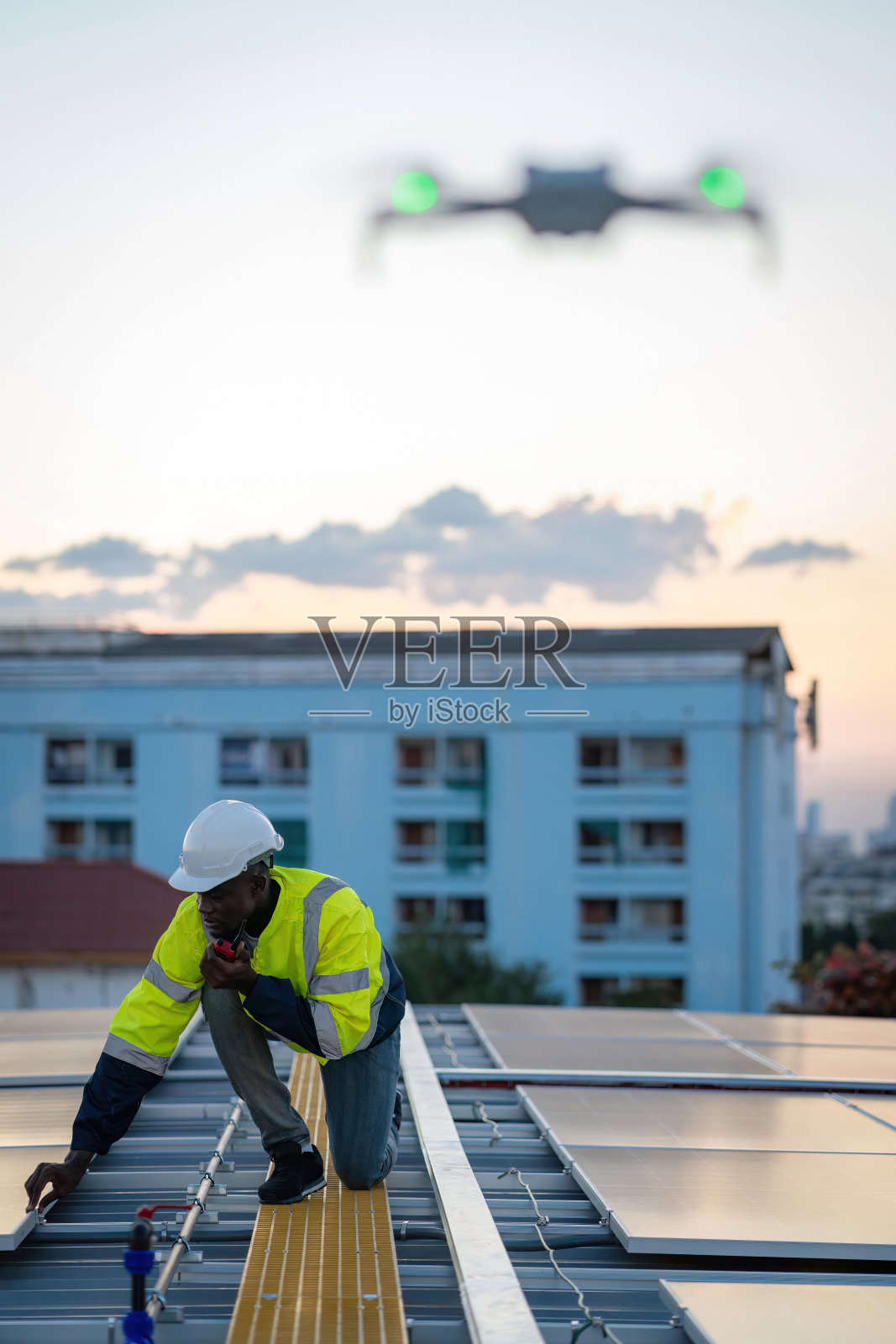 在生态太阳能农场工作的技术员。可再生清洁能源技术理念。专业工程师操纵无人机检查工厂屋顶安装太阳能屋顶板的俯视图照片摄影图片