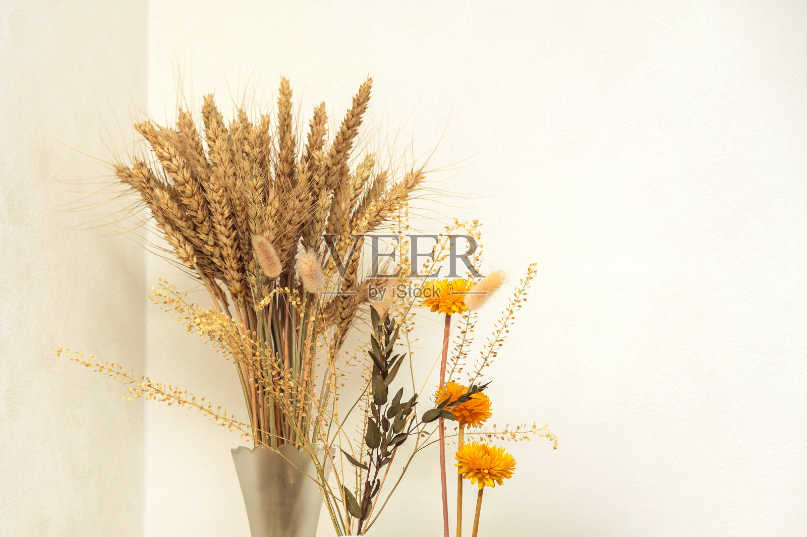 模板与空白相框。花束与干黄花,小麦穗在花瓶。一杯咖啡。白色的墙。照片摄影图片