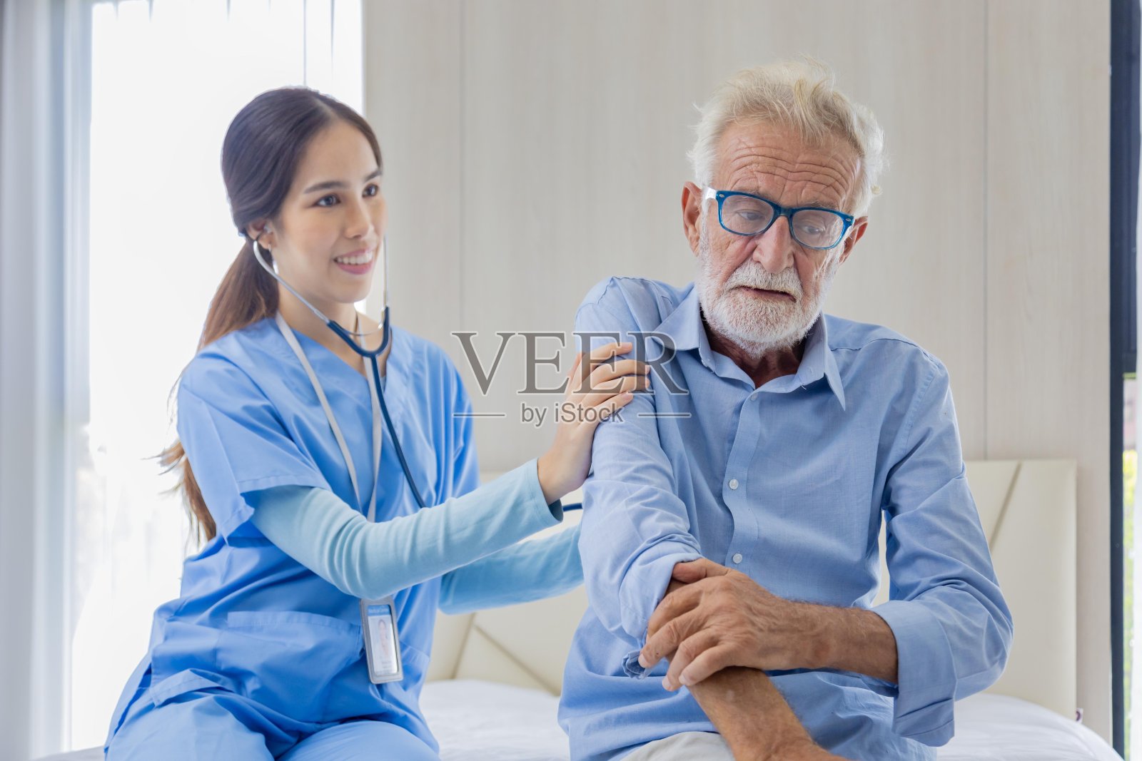 在养老疗养中心,临终关怀护士正在用听诊器对躺在床上的白人男性进行吸烟肺癌诊断照片摄影图片