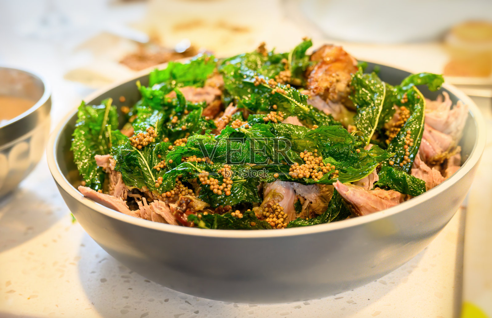 在厨房台面上的碗里放上薄荷和芥菜籽的烤羊肉。家庭烹饪和娱乐的概念。照片摄影图片