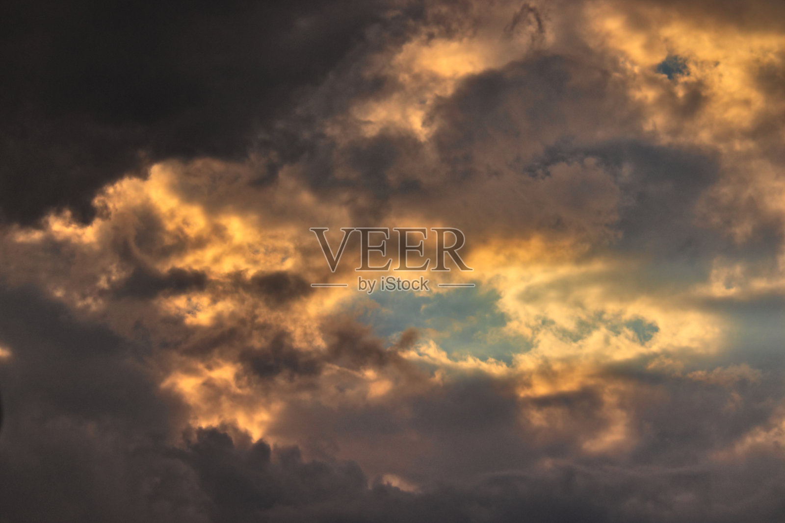 一小片蓝天,被云包围,被暮色笼罩。照片摄影图片