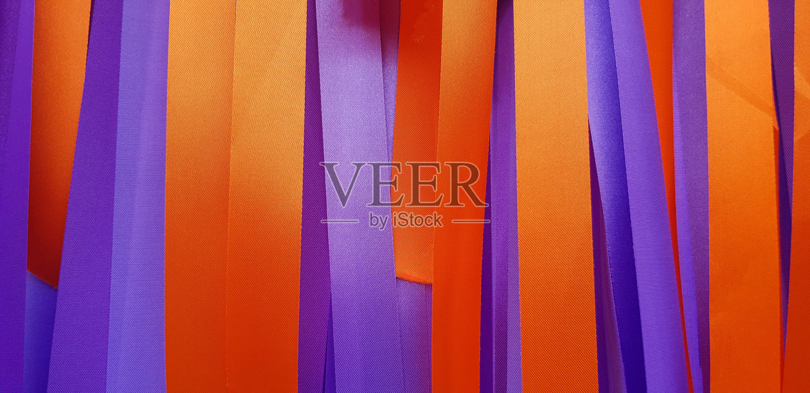 紫色或紫色和橙色丝带背景或墙壁。粉彩纸或织物装饰在聚会,节日,婚礼,新年和庆祝概念。照片摄影图片