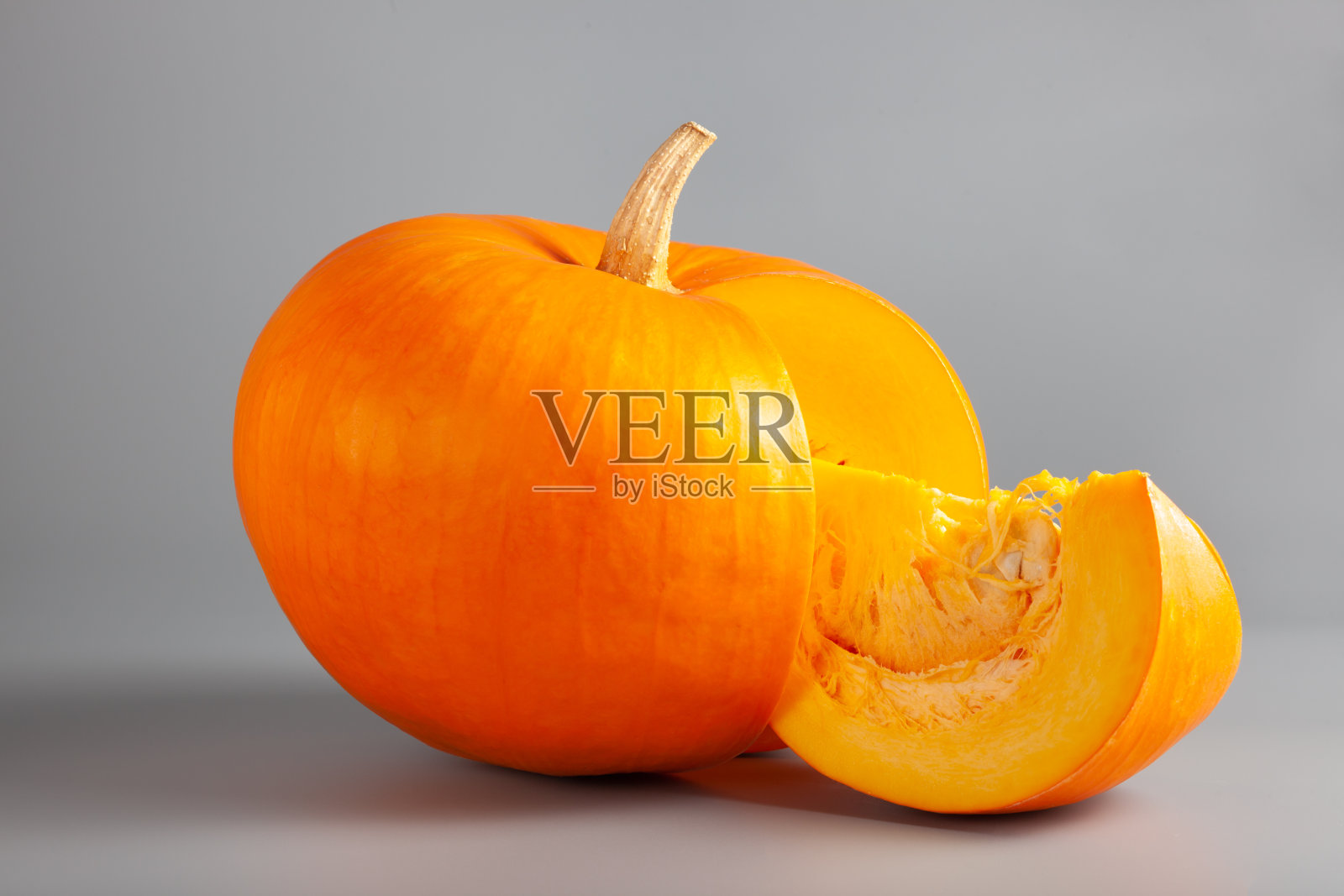 大熟透的橙色南瓜,在灰色背景上切成一片照片摄影图片