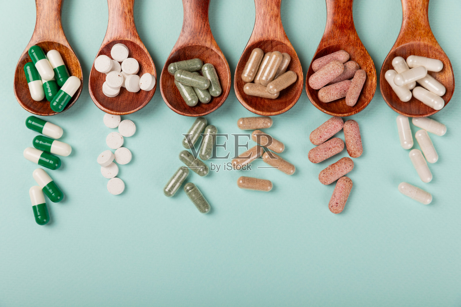维生素和补品。多种维生素片在木勺纹理背景。多吃新鲜健康的水果。食品补充剂。平的。文本空间。本空间照片摄影图片