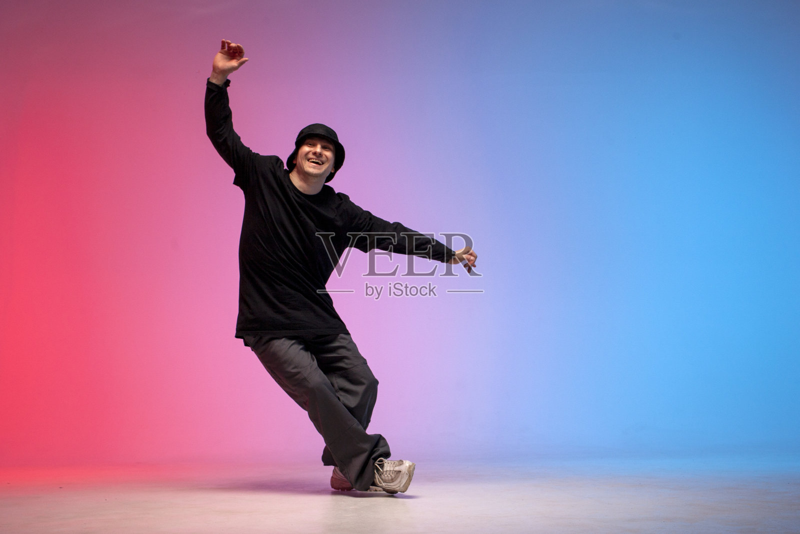 穿着黑色衣服的年轻舞者在霓虹灯下跳霹雳舞,男子在红蓝俱乐部表演嘻哈动作照片摄影图片