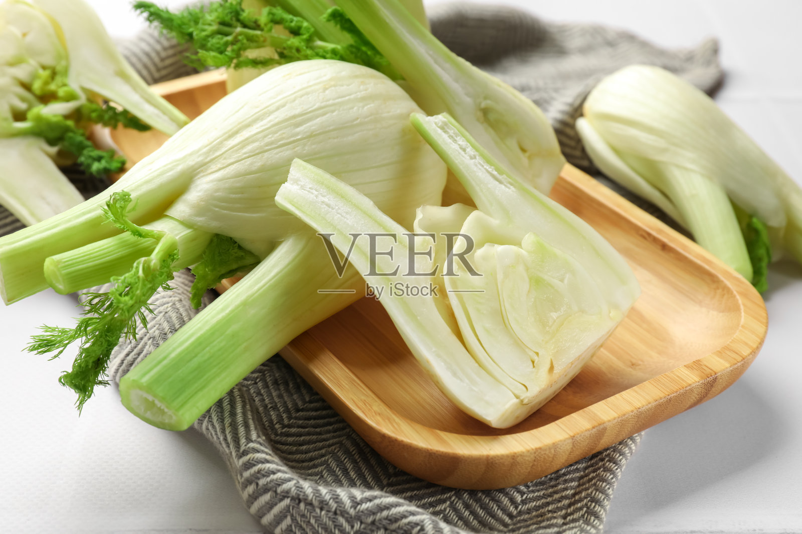 白色桌子上整颗和切碎的茴香球茎,特写照片摄影图片