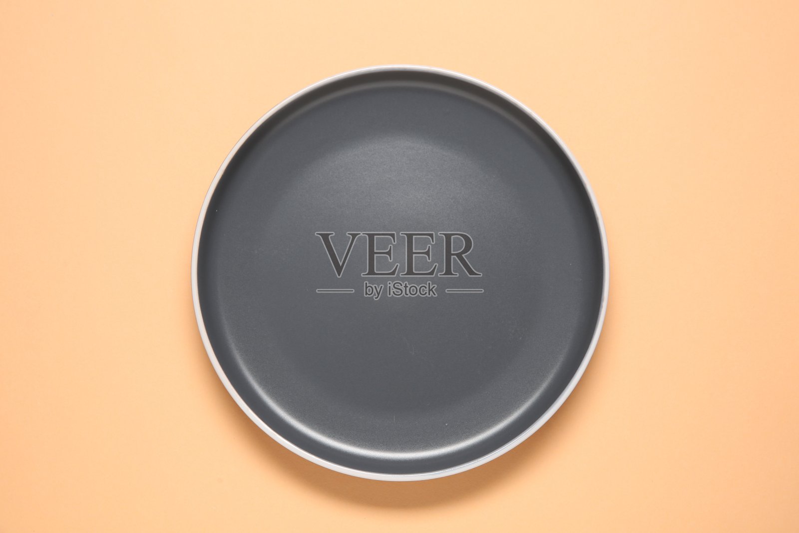 一个灰色陶瓷盘子,米色背景,俯视图照片摄影图片