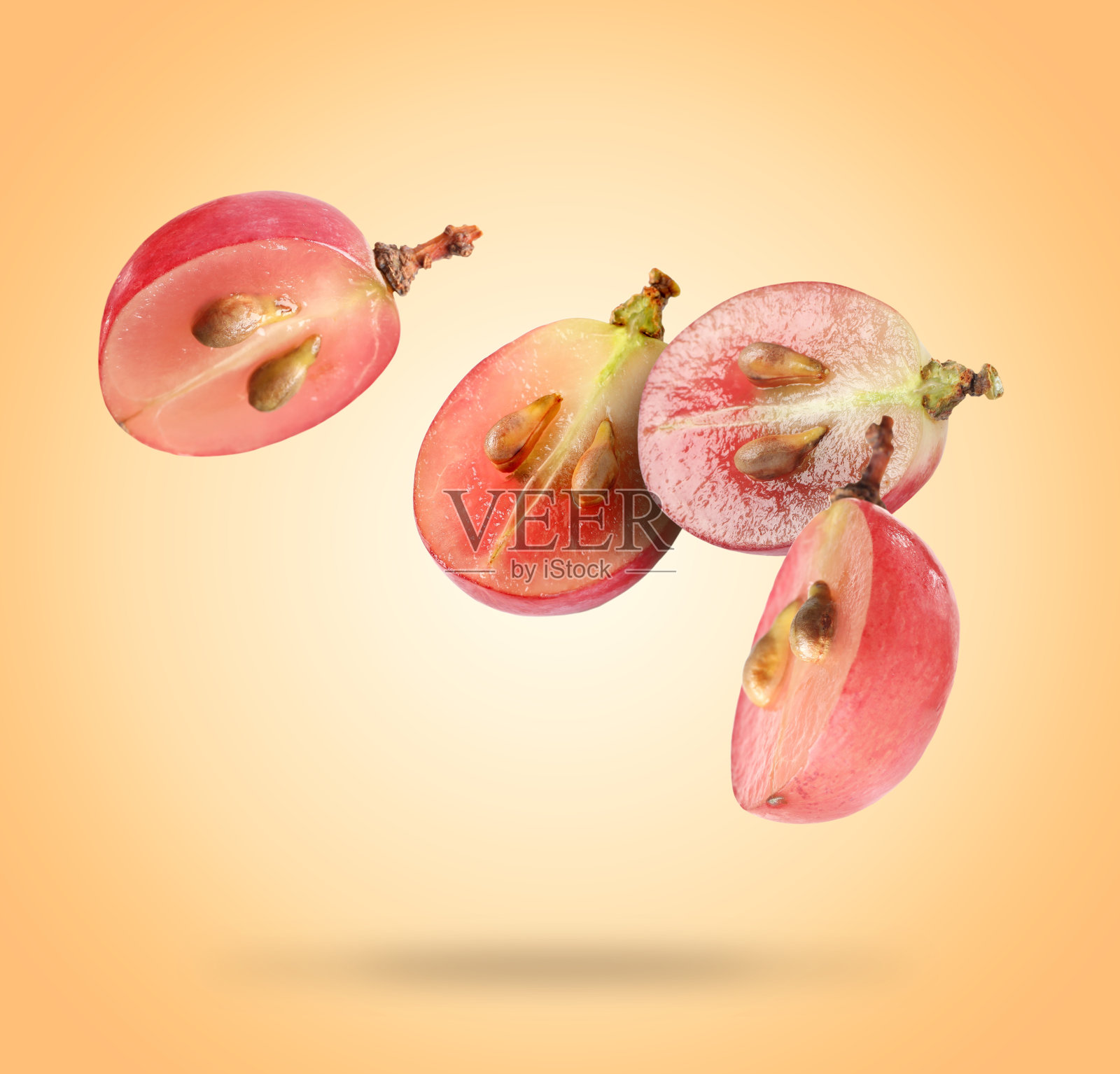 半颗新鲜的葡萄落在淡橙色的背景上照片摄影图片