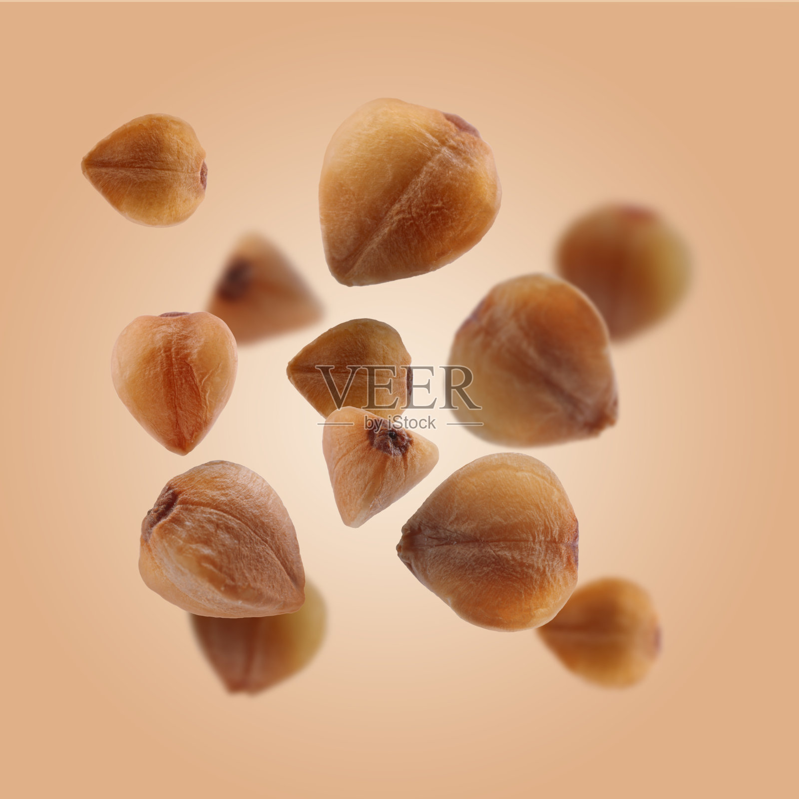 荞麦在淡橙色的背景上飞舞。空气中的颗粒照片摄影图片