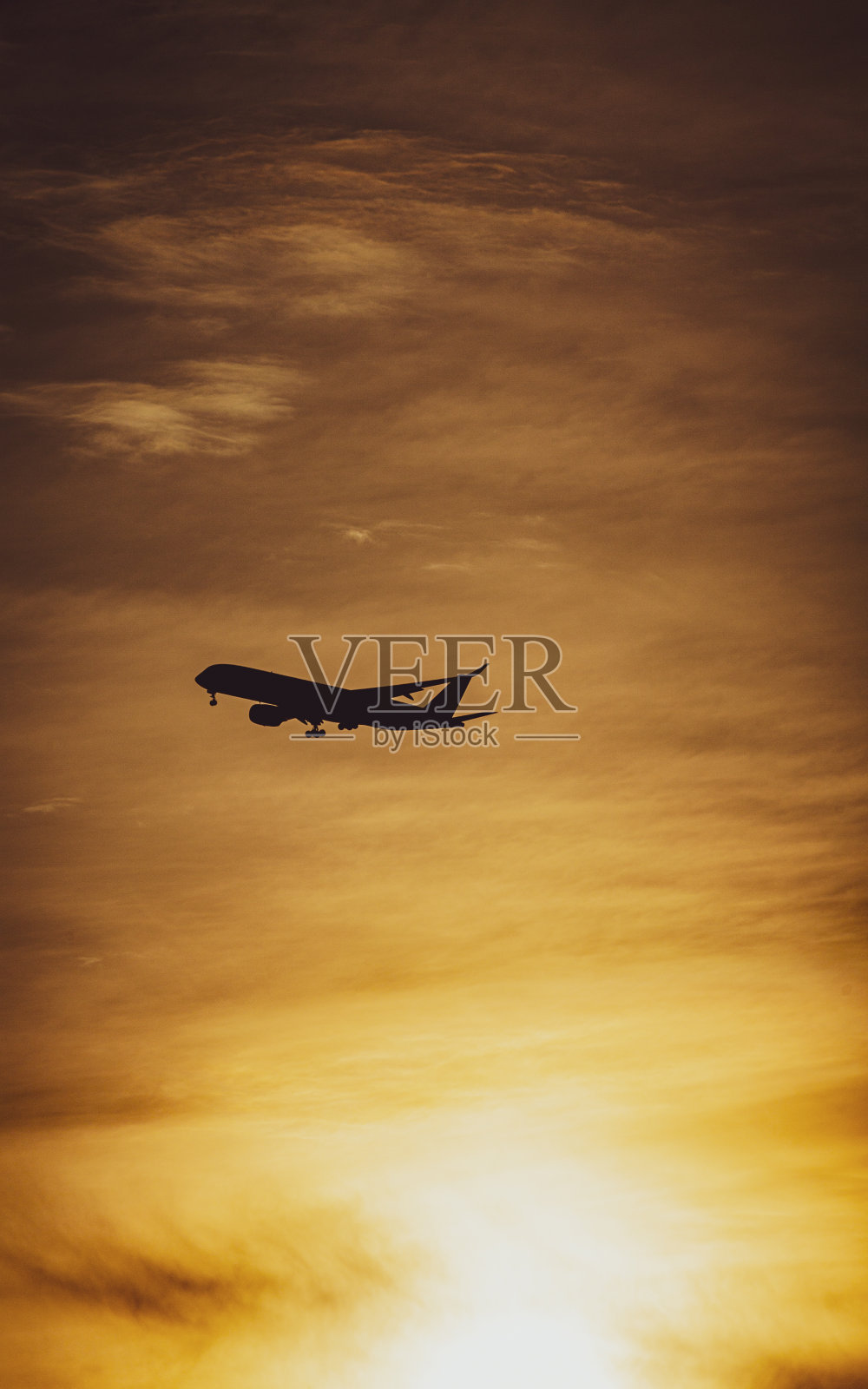 飞机在夕阳的天空中飞行照片摄影图片