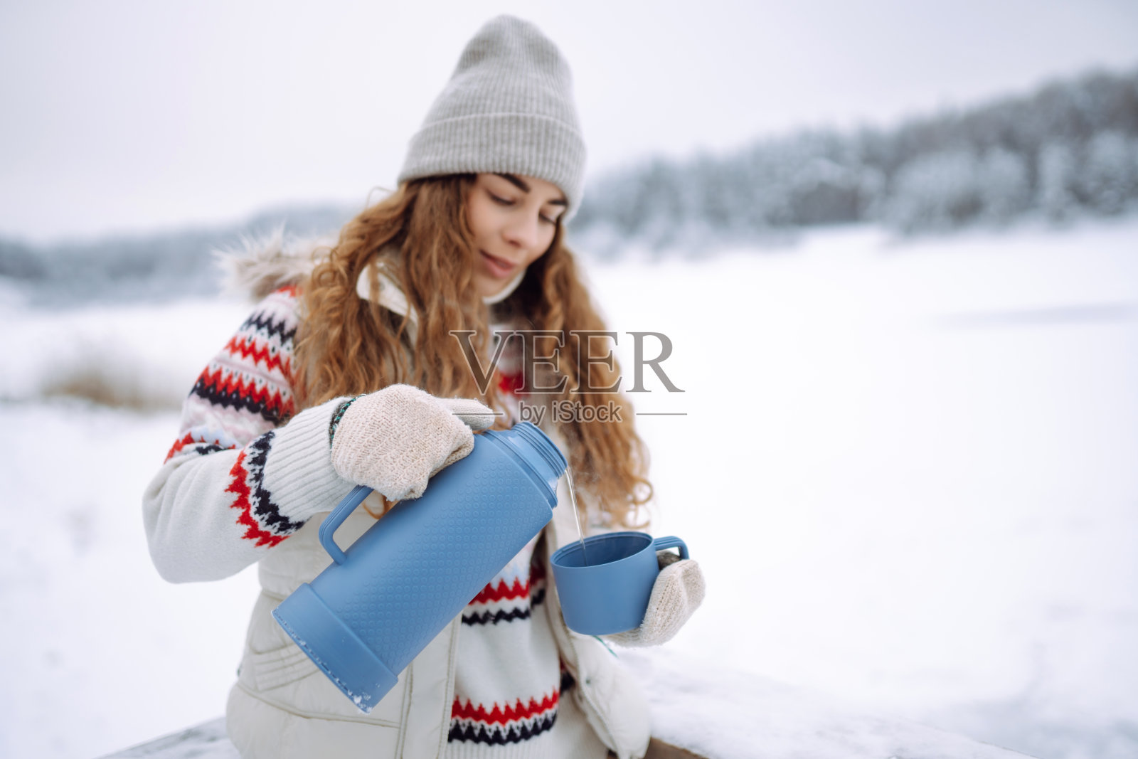美丽的年轻女子用保温瓶喝茶。照片摄影图片