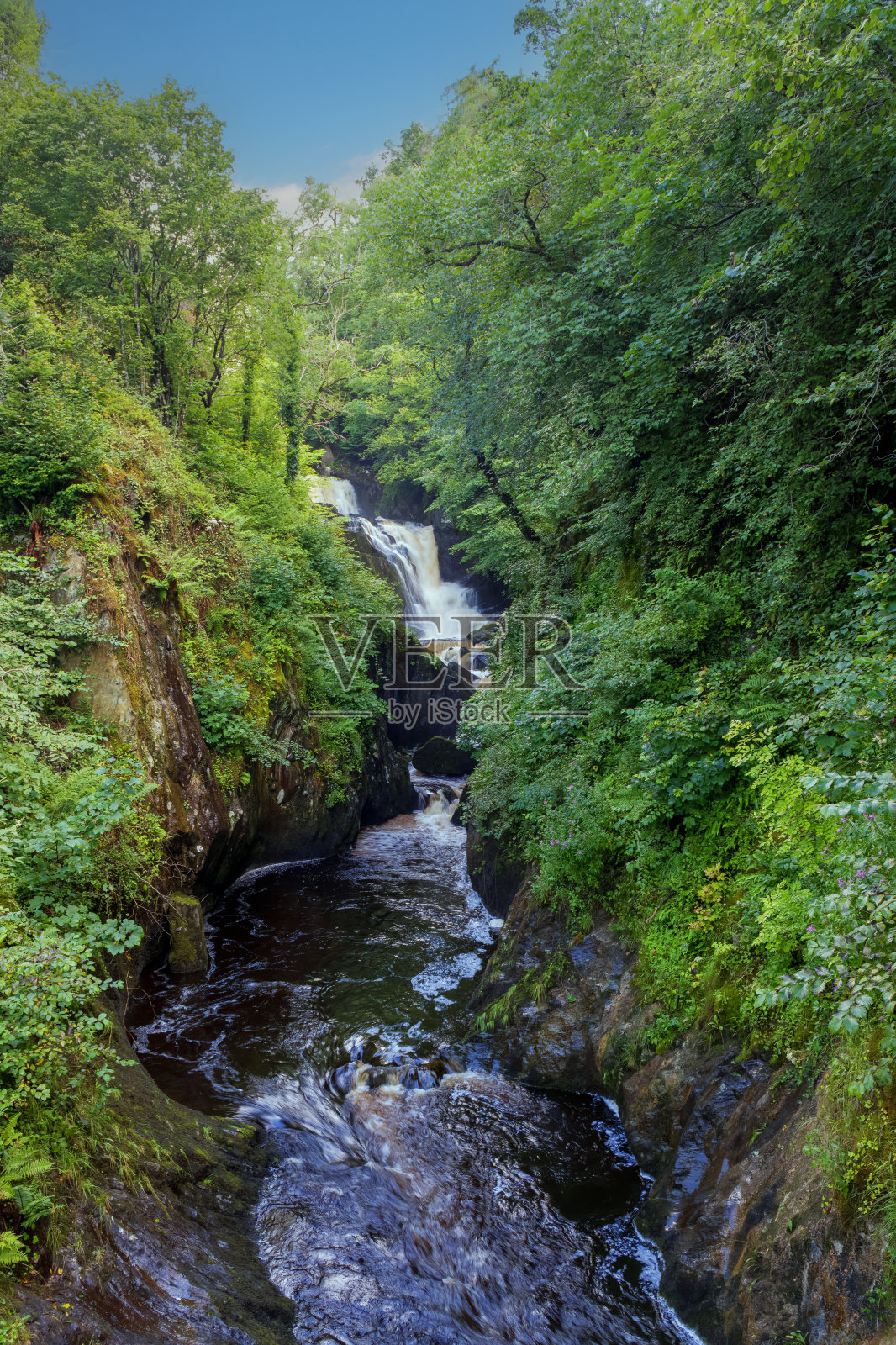 在英格兰的约克郡山谷国家公园,水流过瀑布,流入狭窄的峡谷。照片摄影图片