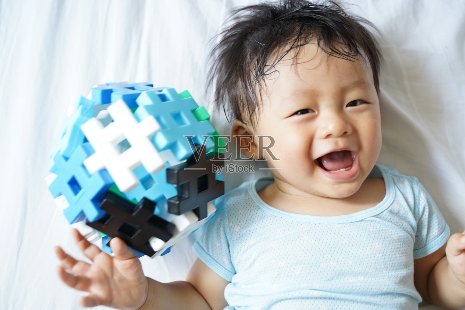 微笑的婴儿拿着积木做的球照片摄影图片