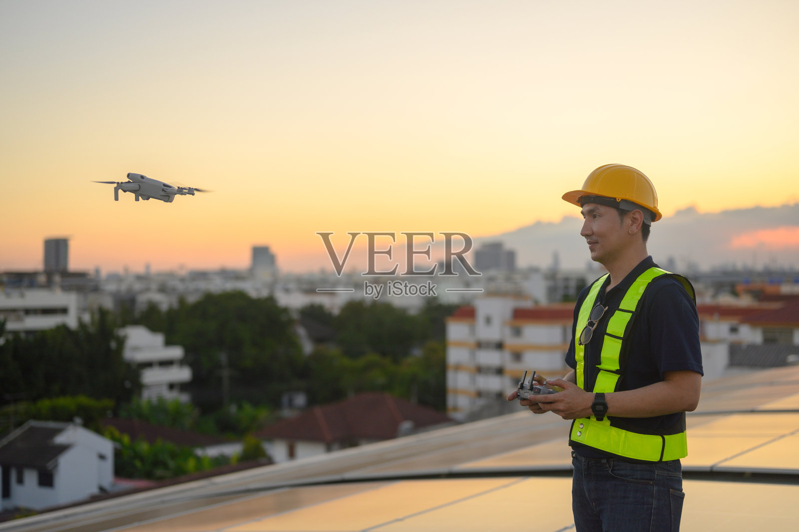 一名男工程师正在屋顶上安装太阳能电池板。在商业建筑屋顶上安装太阳能电池板或光伏电池的工程师或工人。照片摄影图片