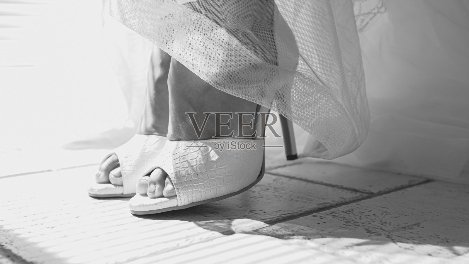 特写:白色礼服被撩起,新娘展示她美丽的新娘鞋照片摄影图片