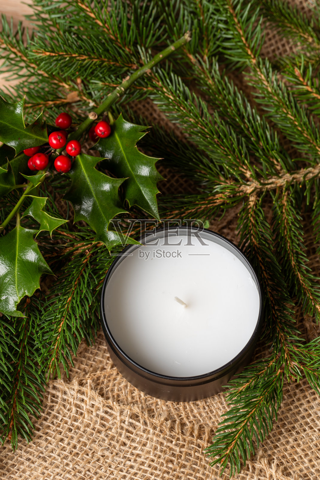 节日桌上的蜡烛。蜡烛立在冷杉树枝做成的圣诞花环上。圣诞节的背景照片摄影图片