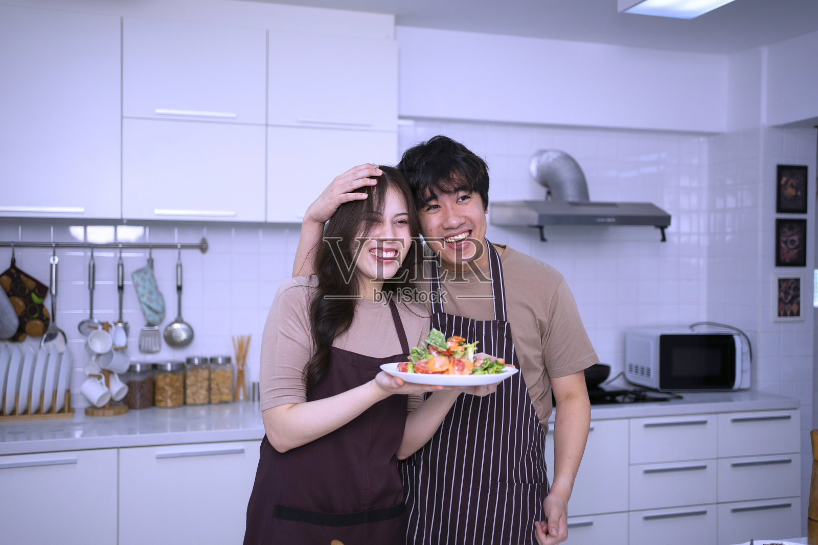 一对年轻夫妇正在厨房做饭。照片摄影图片