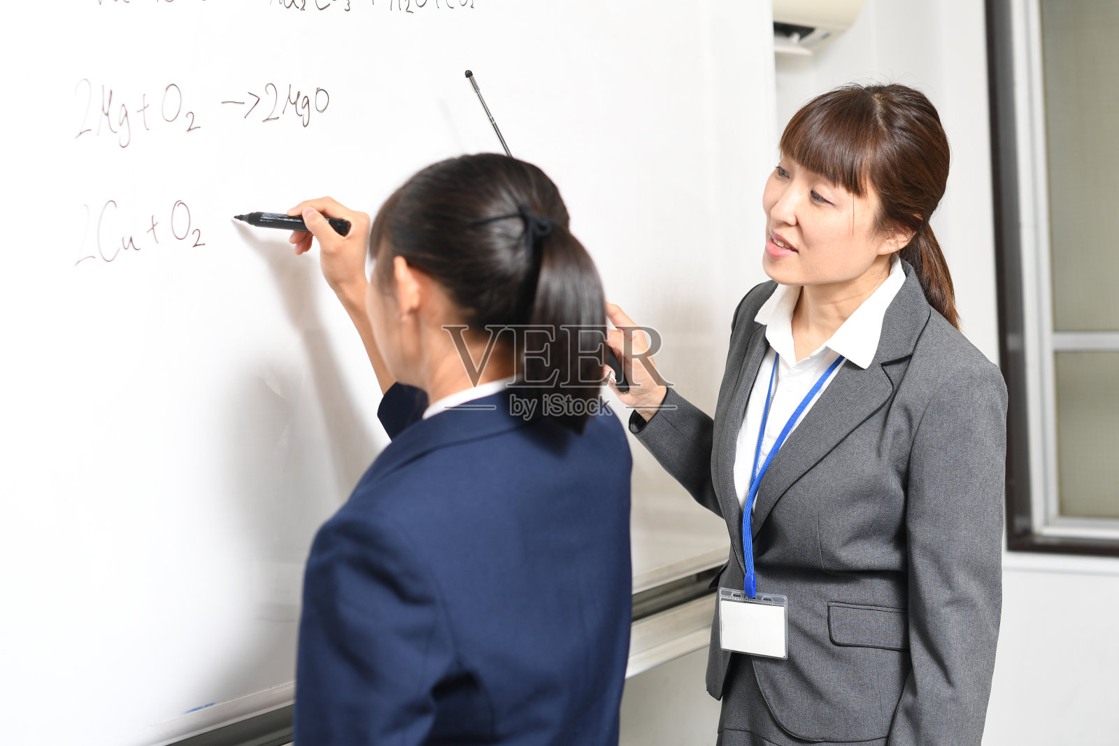 亚洲女学生和女老师让亚洲女学生在教室的白板前回答照片摄影图片