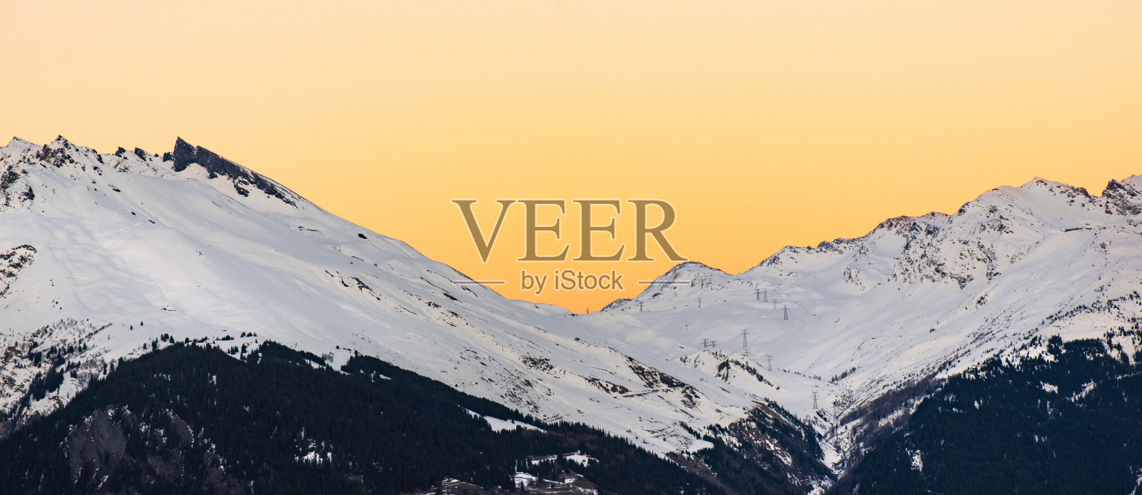 日落在高山山谷的雪峰上照片摄影图片