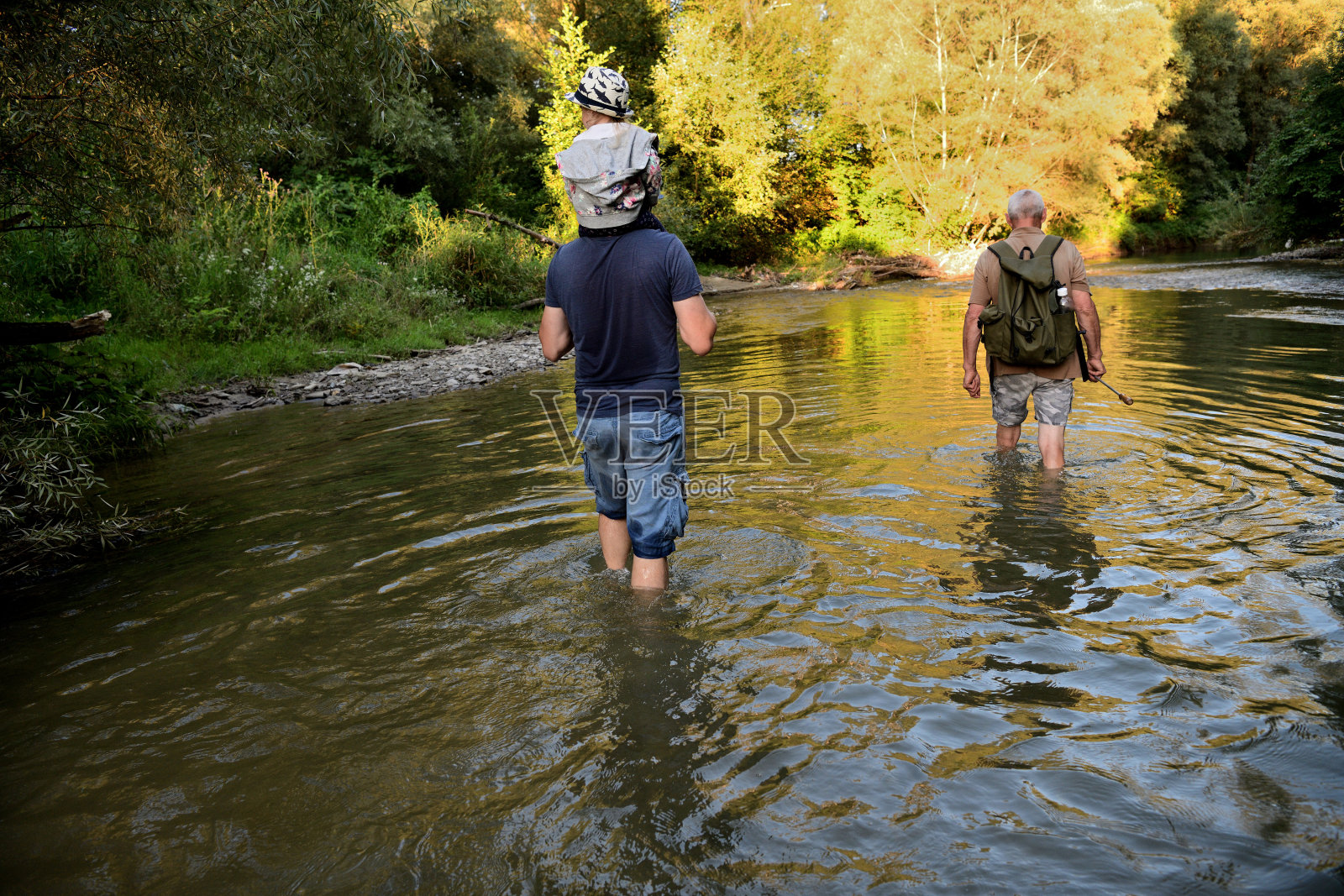 一家人在一条浅河里走向一个露营海滩照片摄影图片
