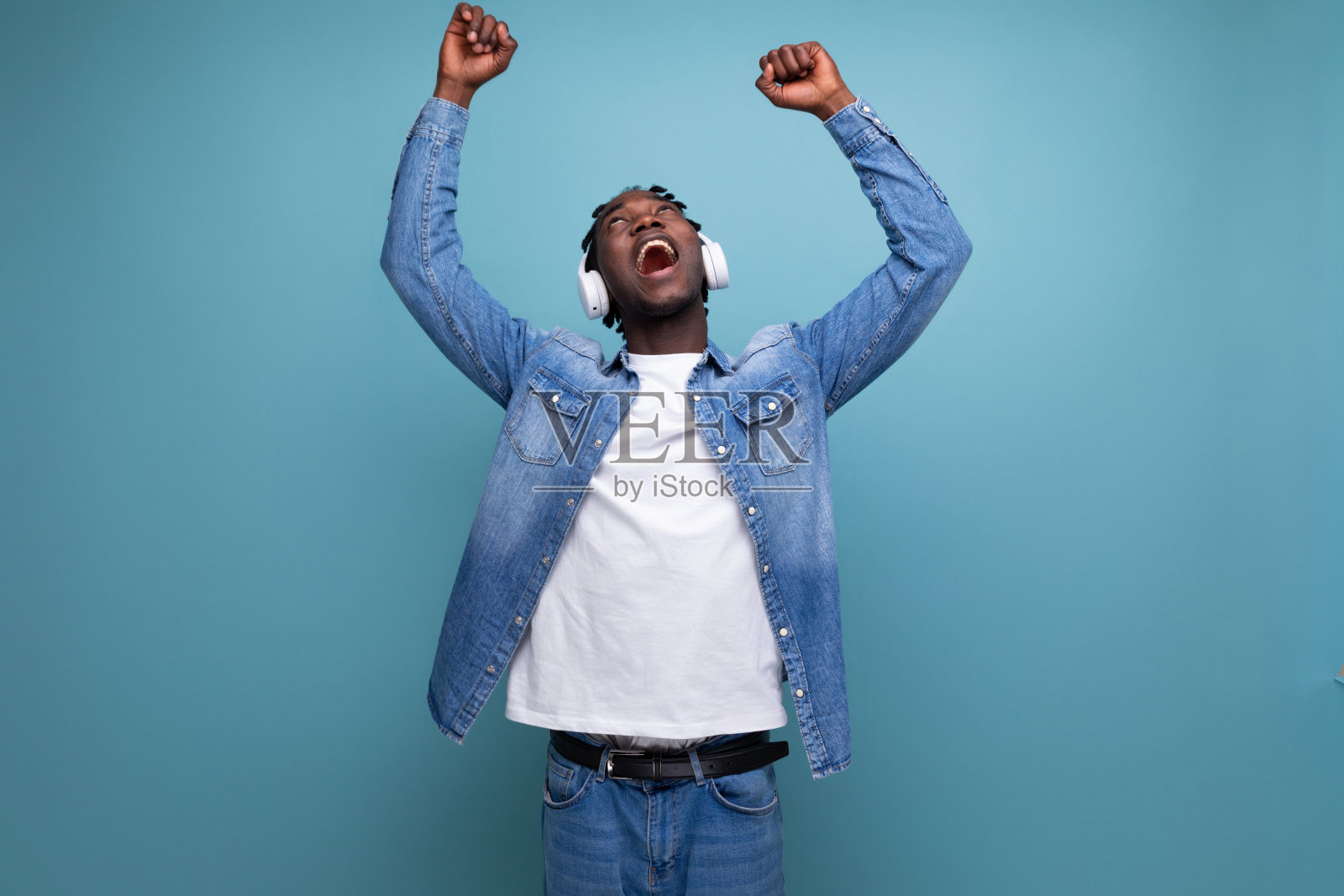 酷哥美国人,留着脏辫,穿着牛仔夹克,戴着耳机听着最喜欢的音乐播放列表照片摄影图片