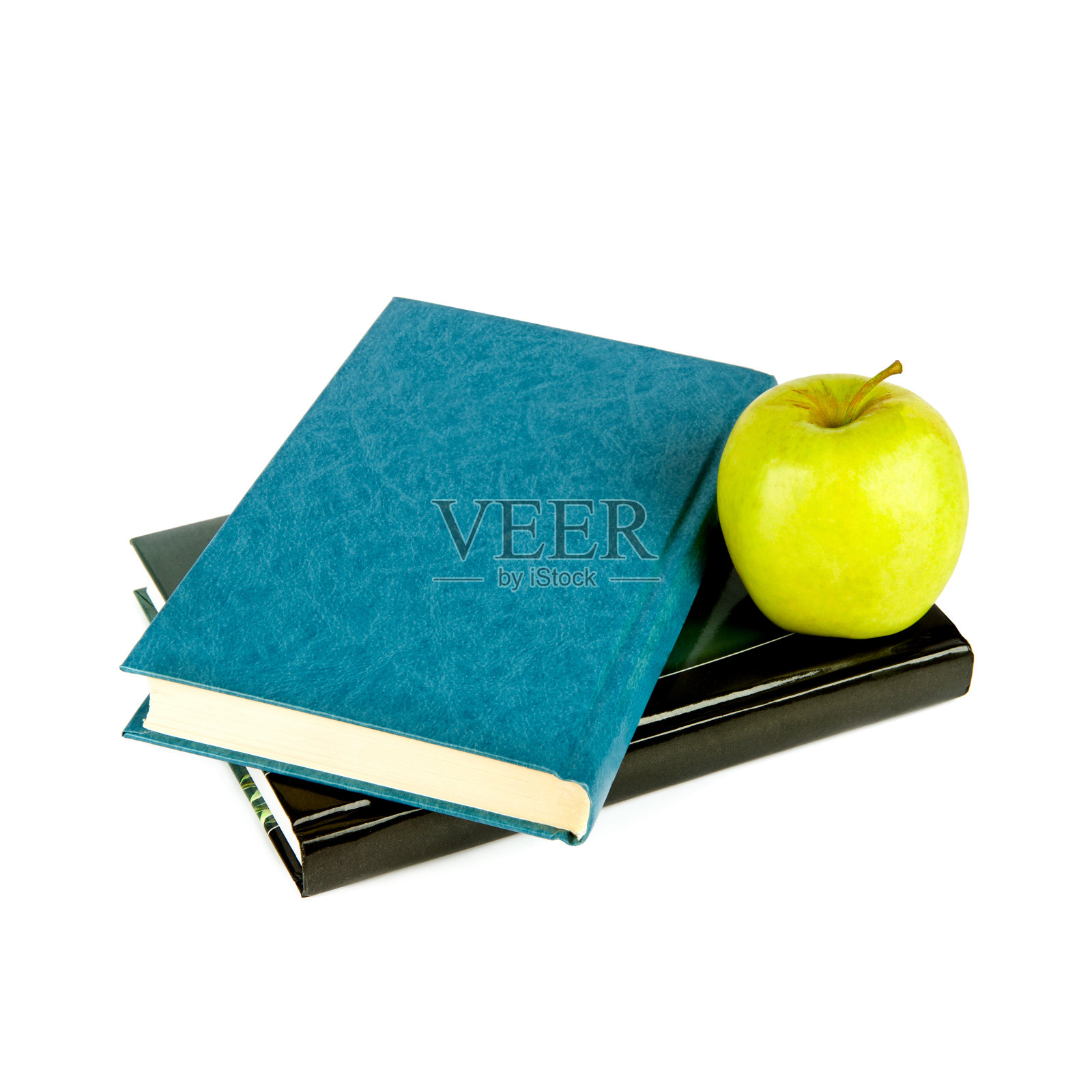 书与青苹果隔绝于白色之上。照片摄影图片