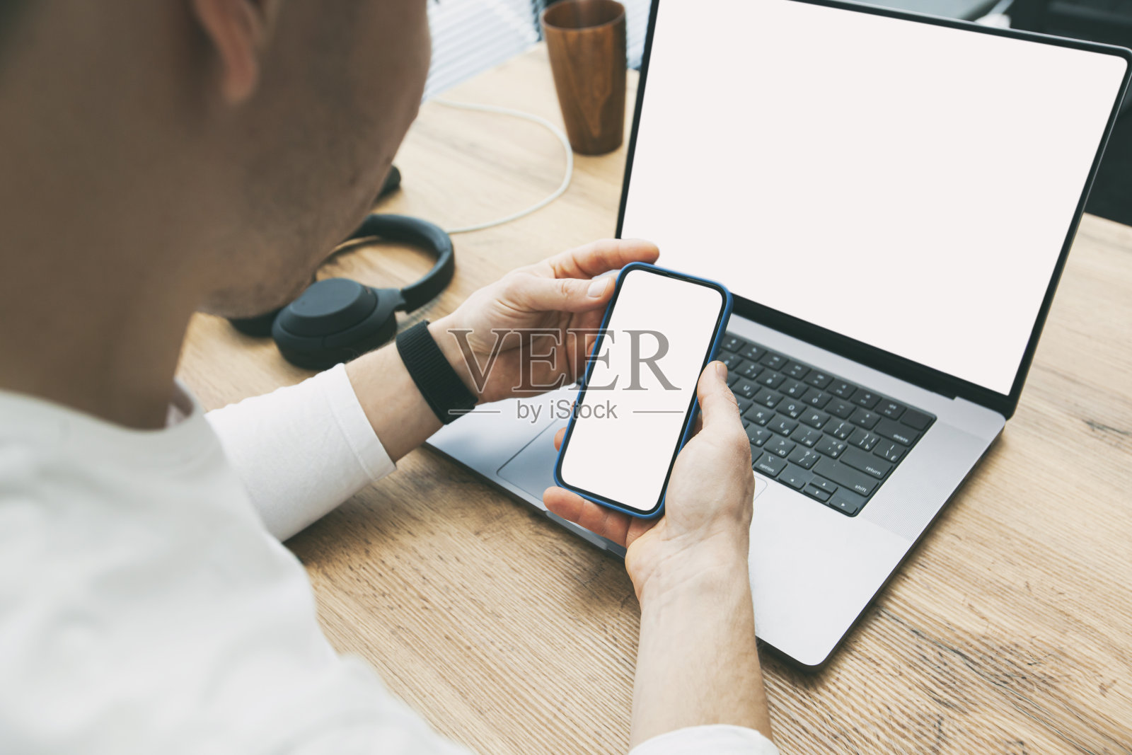 年轻人在家里的桌子上用笔记本电脑和智能手机模型工作。手机用白色复制空间屏幕照片摄影图片