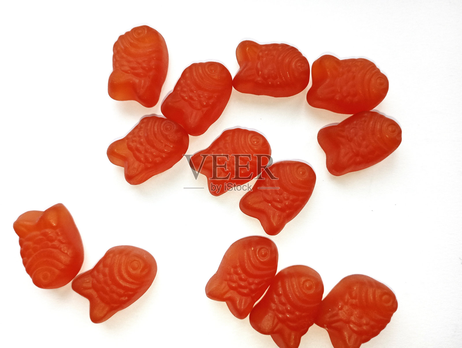 以白色背景的红色水母的形式为儿童提供维生素。对身体发育有益的糖果和药物。照片摄影图片