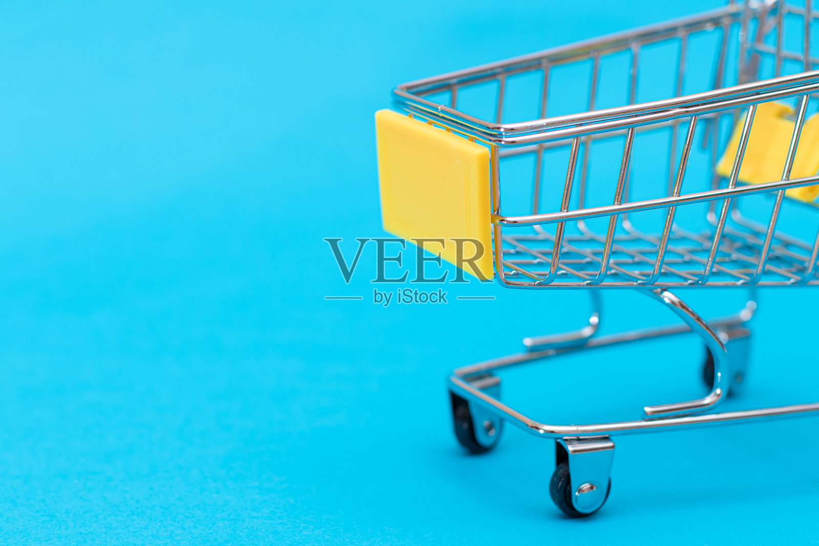 蓝色背景上的空黄色购物车照片摄影图片