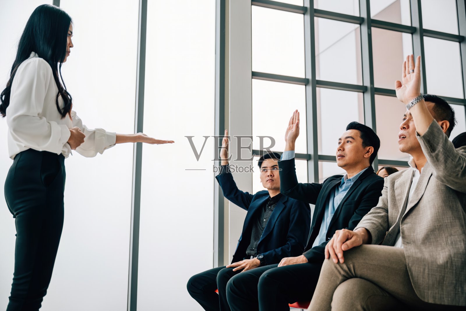 在一次会议上,一个年轻人举手提问,促进了团队合作和小组讨论。主动学习和观众参与是显而易见的。照片摄影图片