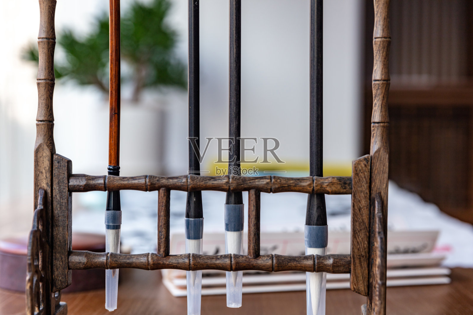 木桌上多支中国毛笔和绿色植物照片摄影图片