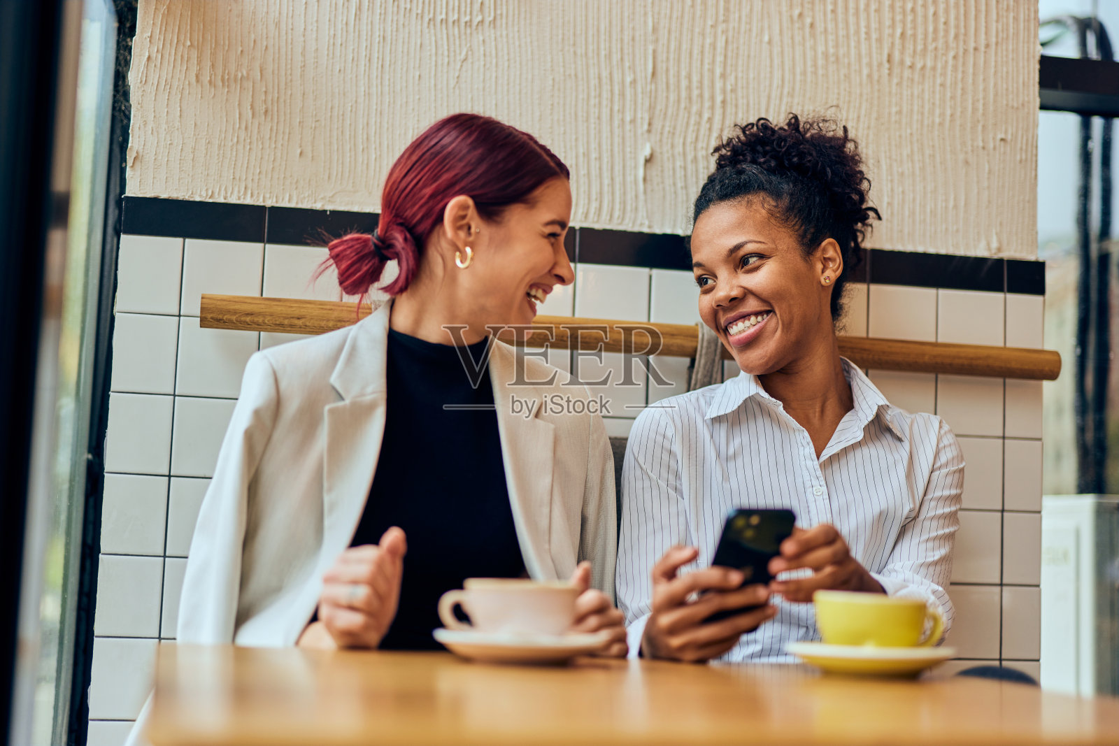 两个成年朋友在咖啡馆享受下午的时光,互相交谈,面带微笑。照片摄影图片