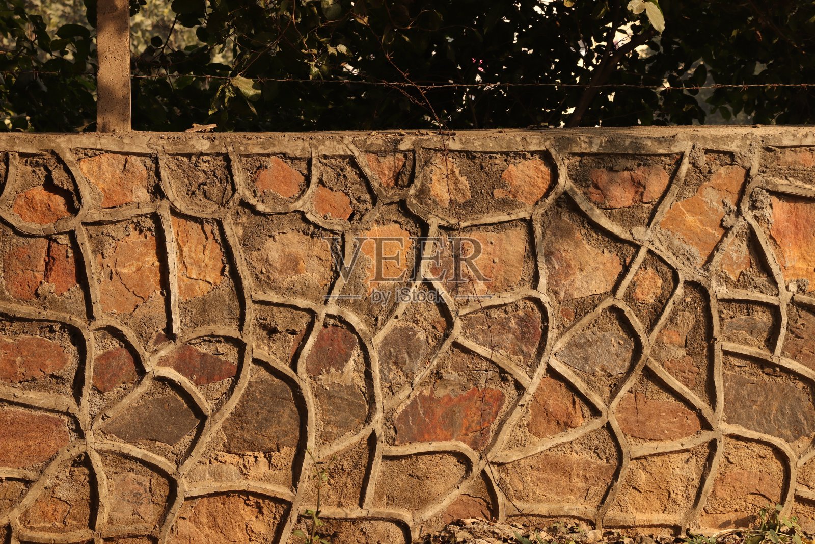 一堵由锌石和棕色复古石组成的墙,在阳光下创造了印度墨西哥风格的石墙设计照片摄影图片