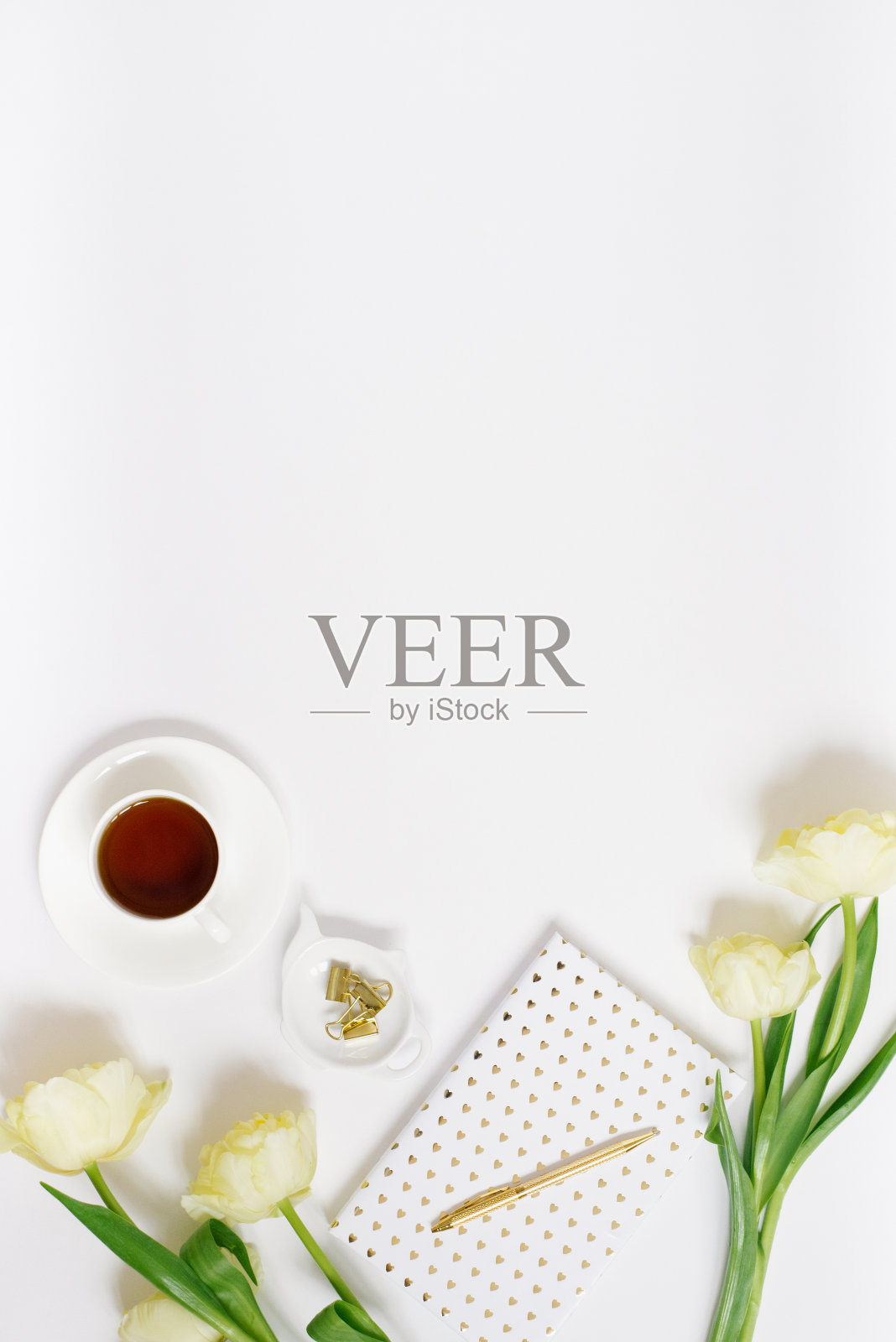 平铺女士办公桌上放着一个笔记本,一束春天的黄花,一杯茶,配件。女性假日桌面视图和复制空间照片摄影图片