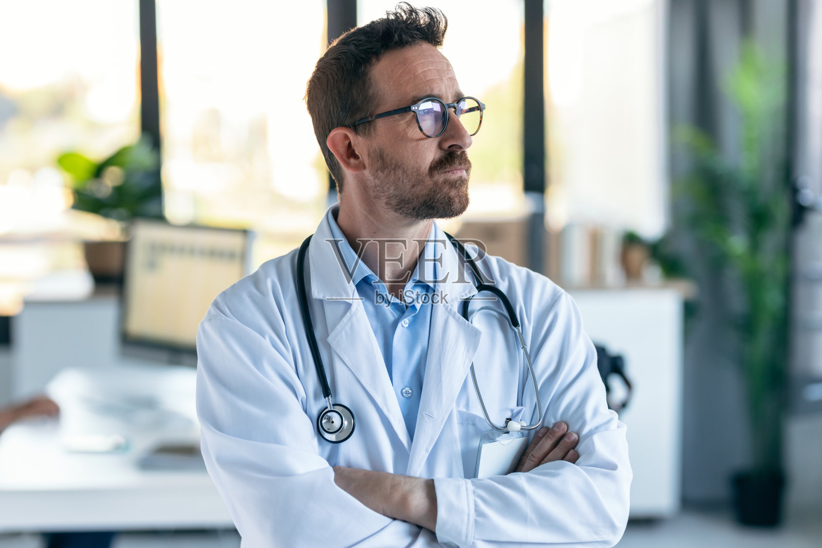 成熟的男医生脖子上戴着听诊器,在会诊时目光向前。照片摄影图片