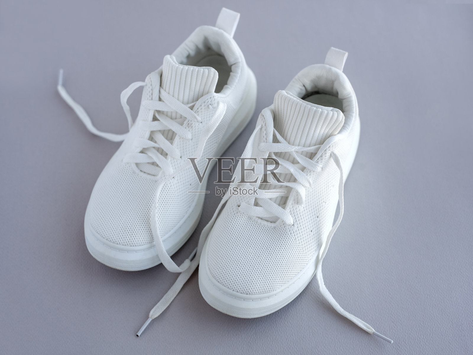 一双灰色底色的白色夏季运动鞋。时尚时尚的运动休闲鞋。鞋店、市场、博客的广告照片摄影图片