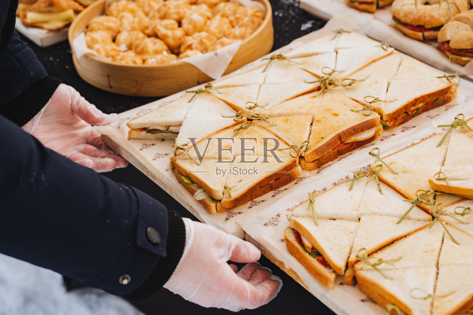 那家伙在桌子上摆了三明治,餐桌摆设,火腿三明治,街上的食物,节日的款待。照片摄影图片