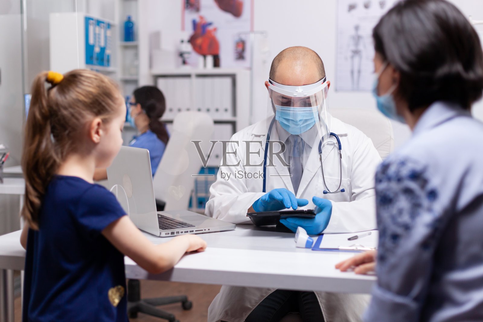 儿科医生在体检时在记事本上写笔记照片摄影图片