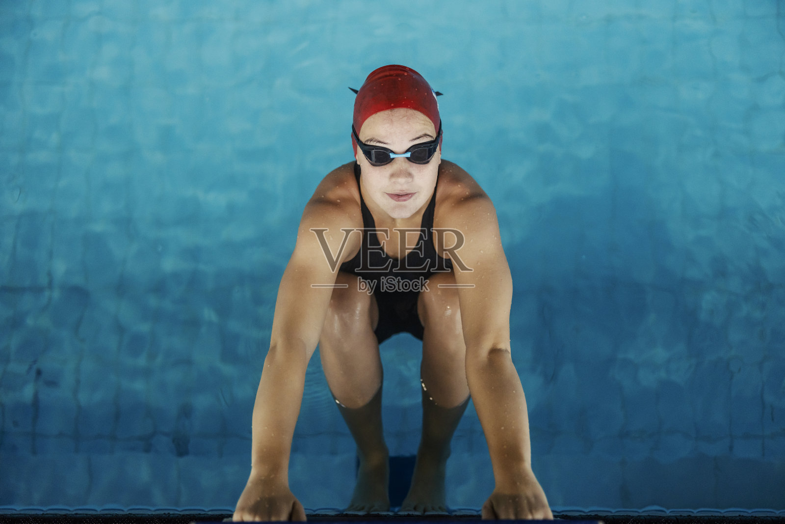 从上面看,一个游泳女孩拿着起跑台,准备起跑。照片摄影图片