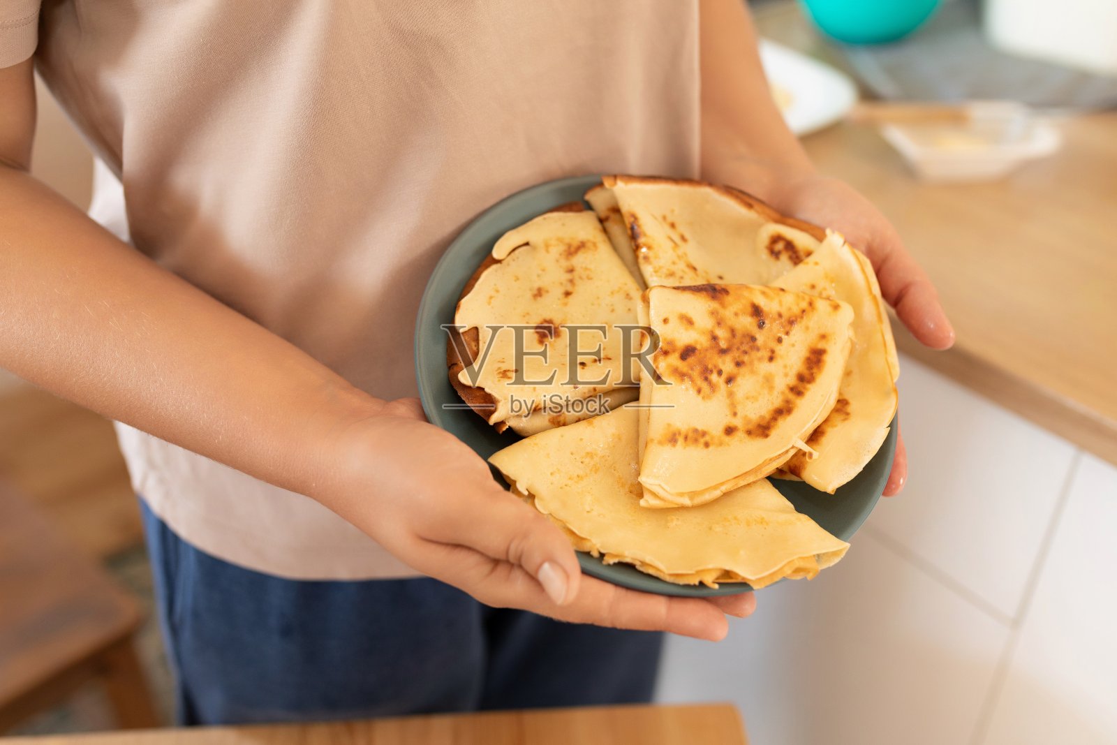 女主人手里的盘子里放着热煎饼照片摄影图片