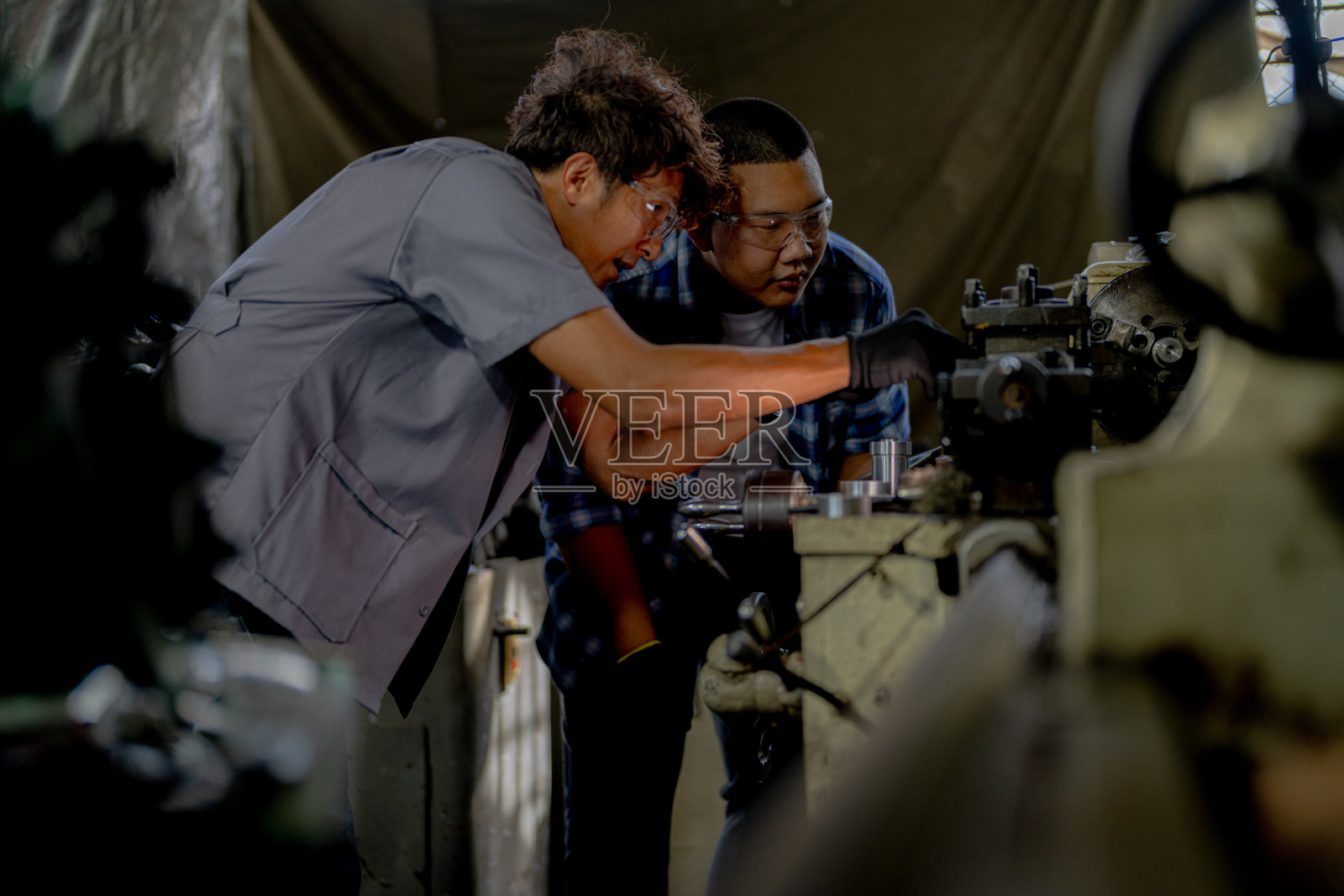 工人们正在检查机器安装用的钢件。一队师生正在钢铁厂学习使用重型机械。工人们在进行产品质量控制时相互配合。照片摄影图片