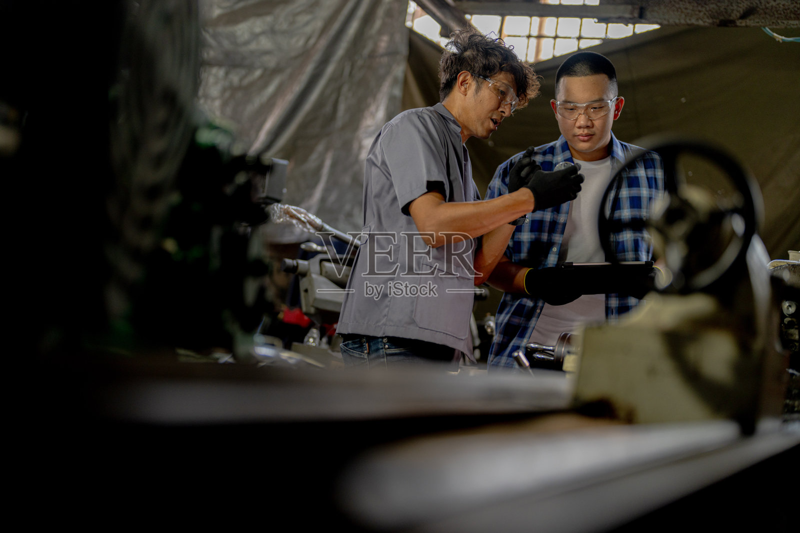 工人们正在检查机器安装用的钢件。一队师生正在钢铁厂学习使用重型机械。工人们在进行产品质量控制时相互配合。照片摄影图片