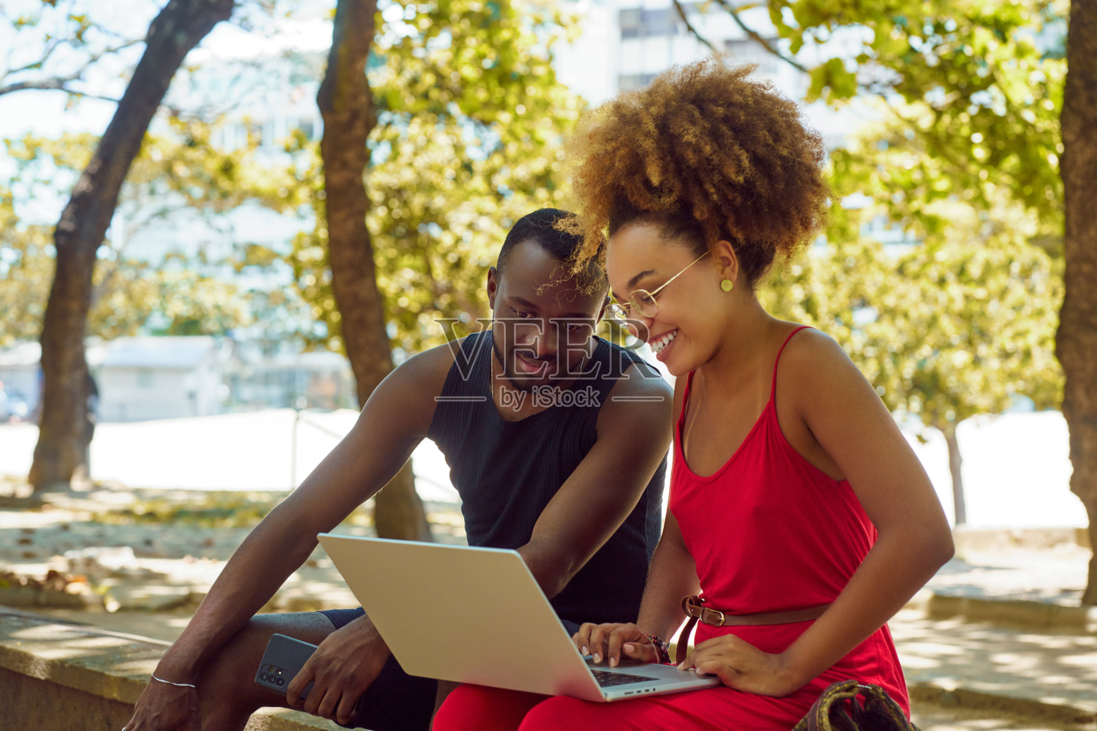 两个年轻的黑人在户外公园里微笑着看着笔记本电脑照片摄影图片