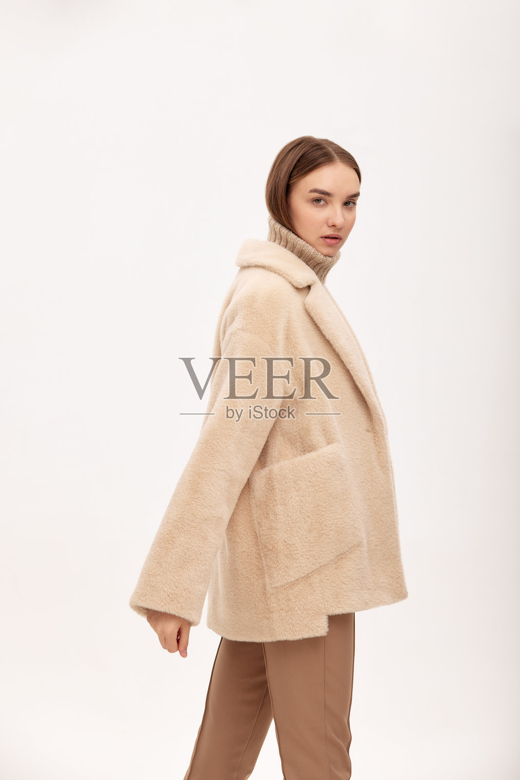 一个漂亮的女商人在浅色背景下穿着皮草大衣,一个市场的照片,一个产品演示,人造皮草,一个女孩穿着人造皮草制成的皮草大衣摆姿势照片摄影图片