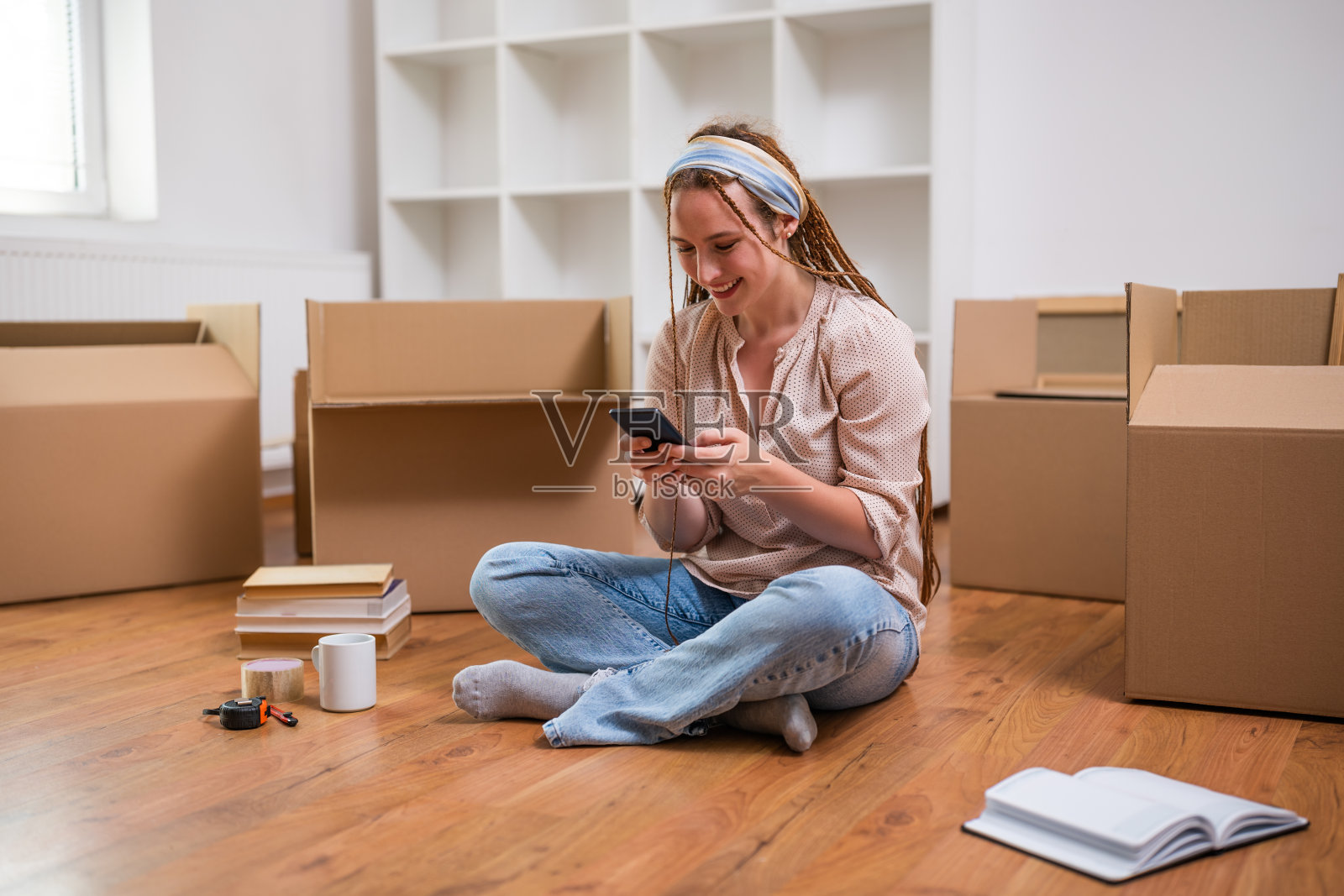 快乐的姜色女人在她的新家使用手机照片摄影图片