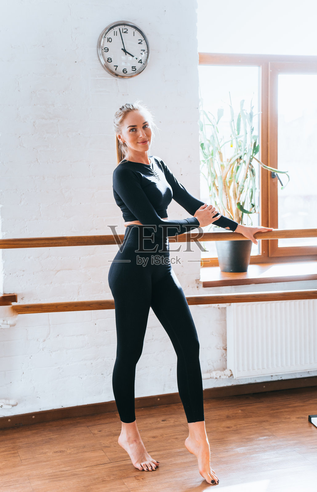 活跃的女性在用巴杠练习芭蕾舞健身,专注而优雅照片摄影图片