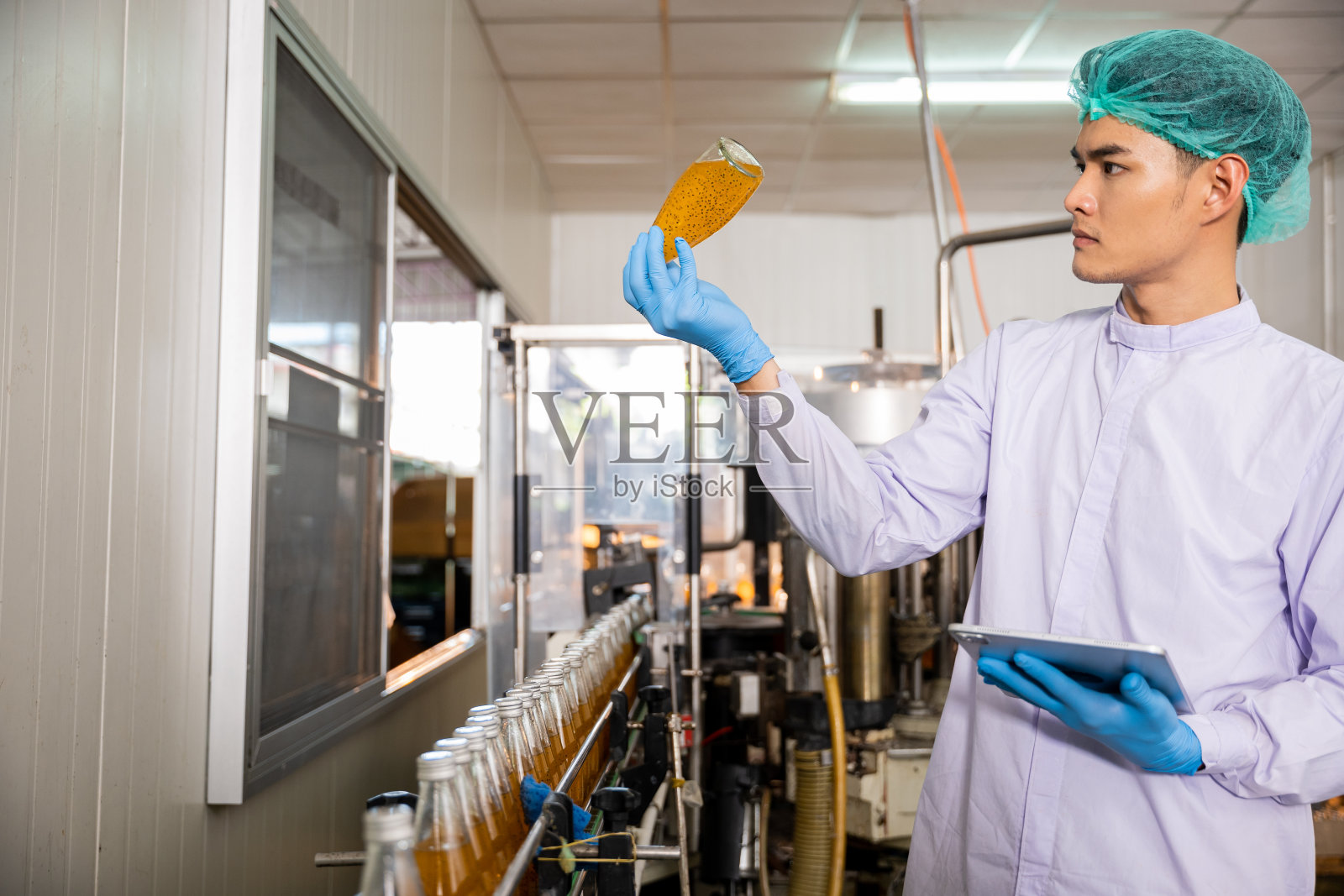 品管员用片剂检查饮料装瓶厂生产线,确保质量一流照片摄影图片
