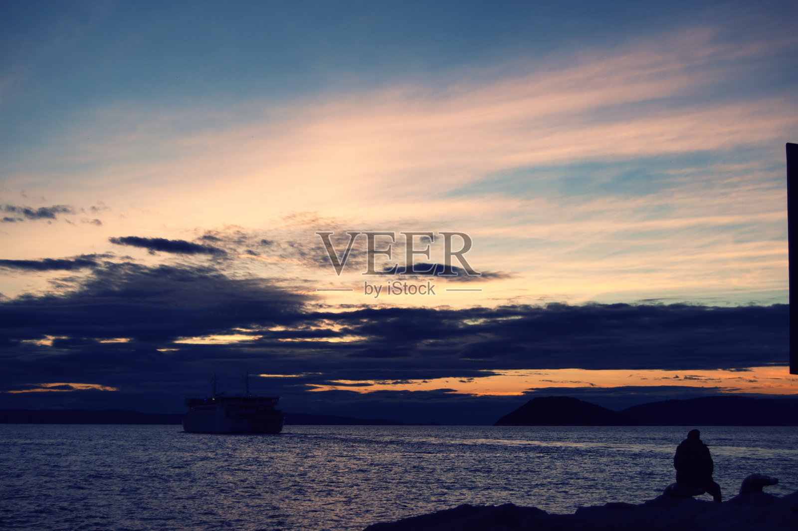 一个人在海边看着渡船驶过照片摄影图片